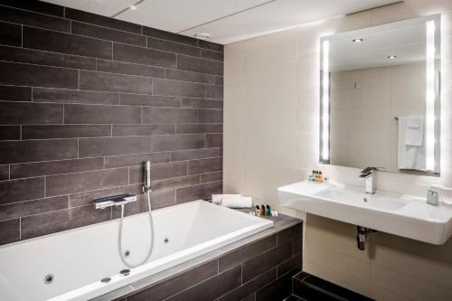 a bathroom with a bath tub and a sink at Holiday Inn Eindhoven Centre by IHG in Eindhoven