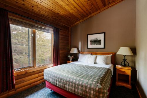 1 dormitorio con cama y ventana grande en Miette Mountain Cabins, en Jasper