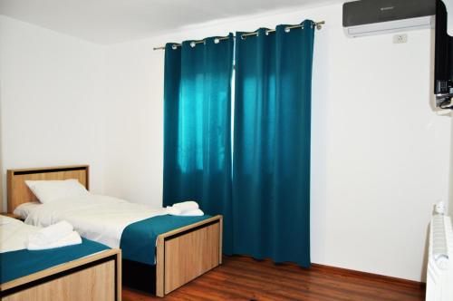 two beds in a room with blue curtains at Pensiunea Corina Tulcea in Tulcea