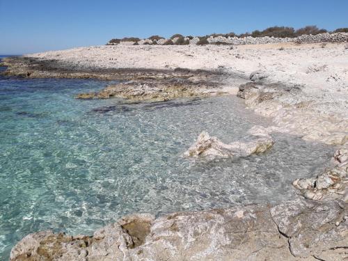 a beach with clear blue water and rocks at SEA YA - two apartments house with heated pool - 150m from beach in Zaglavice