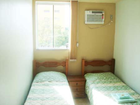 HF Minas Hotel في فيسباسيانو: غرفة صغيرة بسريرين ونافذة
