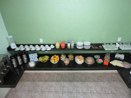 a counter with many bowls and plates of food at HF Minas Hotel in Vespasiano
