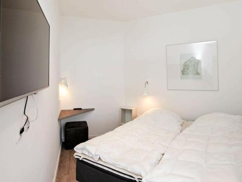 uma cama branca num quarto com uma televisão de ecrã plano em Two-Bedroom Holiday home in Wendtorf 23 em Wendtorf