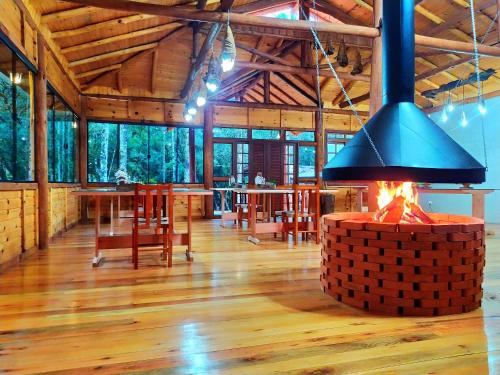 una chimenea en el medio de una habitación con mesas y sillas en Pousada Caminhos da Natureza, en Urubici