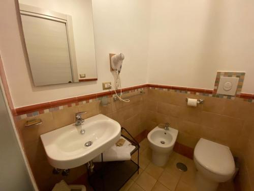 a bathroom with a sink and a toilet and a mirror at V&V Suite & Breakfast in Pompei