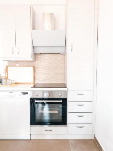 a kitchen with white cabinets and an oven at Αλός αήρ suites in Kithnos