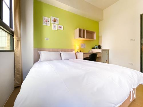 a white bed in a room with a green wall at Adagio Hostel in Taichung