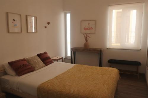 a bedroom with a bed and a table and two windows at Casa Barru in Albufeira