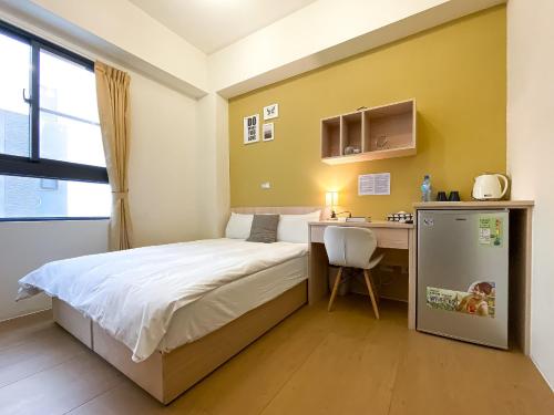 a small bedroom with a bed and a desk at Adagio Hostel in Taichung
