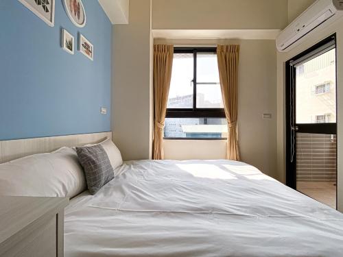 a bedroom with a white bed and a window at Adagio Hostel in Taichung