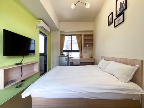 a bedroom with a white bed and a flat screen tv at Adagio Hostel in Taichung