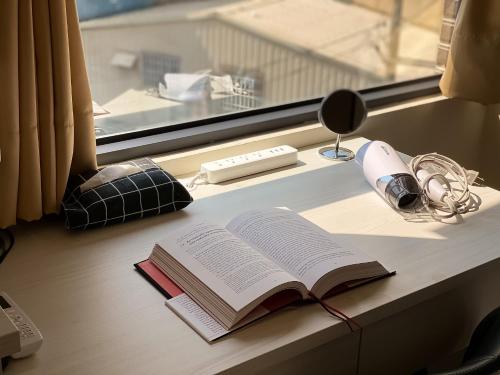 um livro aberto sobre uma mesa ao lado de uma janela em Adagio Hostel em Taichung