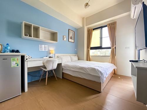 a small bedroom with a bed and a desk at Adagio Hostel in Taichung