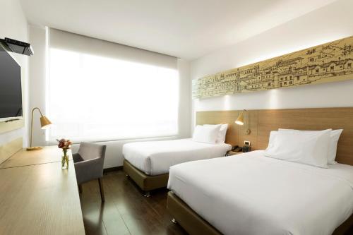 a hotel room with two beds and a large window at Hotel bh Usaquén in Bogotá