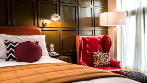 a bedroom with a bed and a red chair at Hotel Indigo York by IHG in York