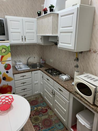een keuken met witte kasten, een wastafel en een magnetron bij Moradia Ricardo - Nazaré in Nazaré