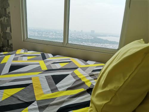 Bett mit farbenfroher Bettdecke vor einem Fenster in der Unterkunft 4 Bed Condo Sleeping by The Sea in Jakarta