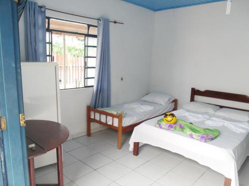 a small room with two beds and a window at Pousada Edson in Caraguatatuba