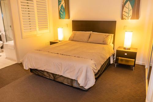 a bedroom with a large bed with two night stands at Marina View Apartment in Airlie Beach