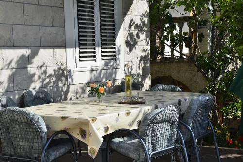 una mesa con sillas y un jarrón de flores. en Apartments Miljas en Cavtat