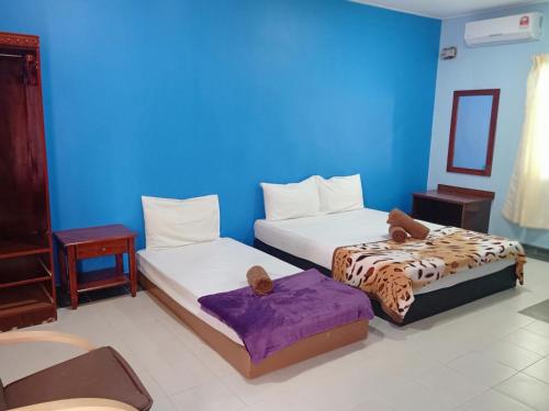 a room with two beds and a blue wall at Drym Valley Langkawi in Pantai Cenang