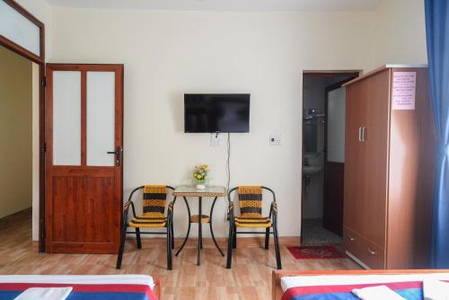 a room with a table and two chairs and a tv at Ahoj Guest House in Ha Long
