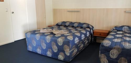 a bedroom with two beds with blue comforter at Mango Tree Motel in Agnes Water