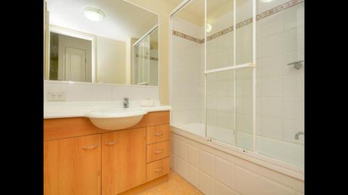 a bathroom with a sink and a shower and a mirror at Mermaid Beach Apartment in Gold Coast