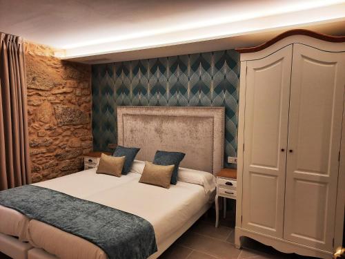 um quarto com uma cama king-size e uma parede de pedra em Solpor do Coído em Muxía