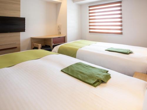a hotel room with two beds and a television at Kuretake Inn Premium Fukuroi Ekimae in Fukuroi