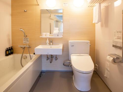 a bathroom with a toilet and a sink and a tub at Kuretake Inn Premium Fukuroi Ekimae in Fukuroi