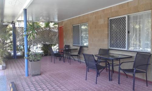 a patio area with chairs, tables, and benches at Mango Tree Motel in Agnes Water