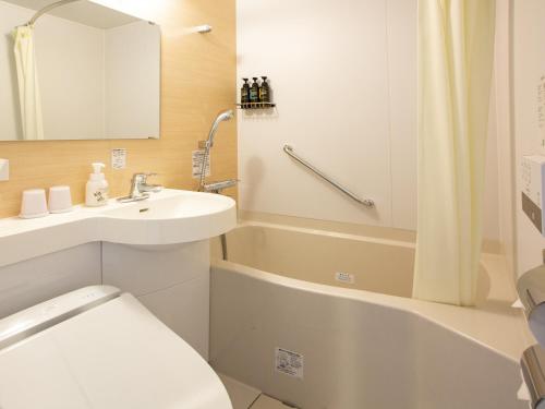 a bathroom with a sink and a toilet and a tub at Kuretake Inn Premium Fukuroi Ekimae in Fukuroi