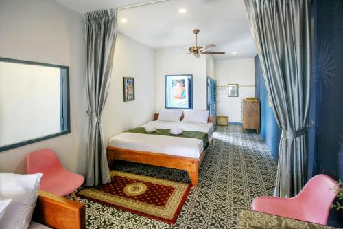 a bedroom with a bed and two pink chairs at Susie Q Designer House in Kampot