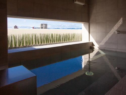 a bathroom with a tub with a view of a field at Kuretake Inn Premium Fukuroi Ekimae in Fukuroi