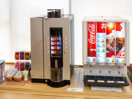 a drink dispenser next to a cocacola machine at Kuretake Inn Premium Fukuroi Ekimae in Fukuroi