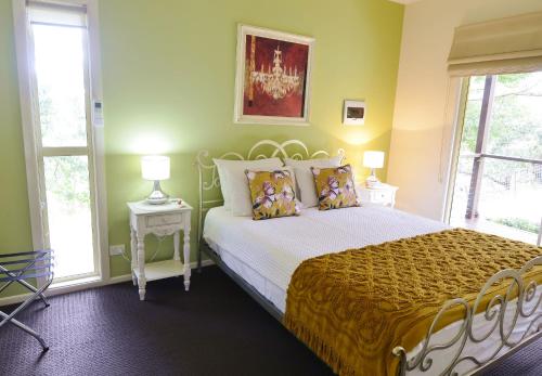 a bedroom with a bed with yellow walls and windows at Apple Tree Cottage Montville in Montville