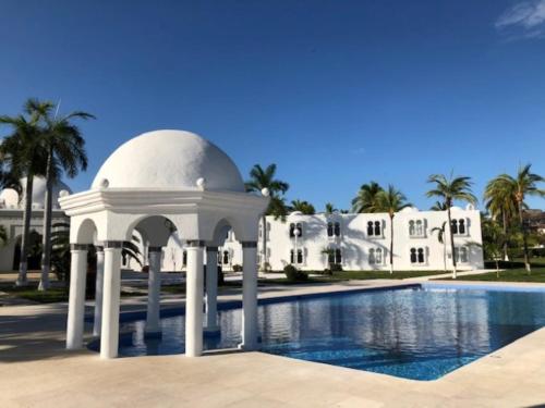 a white gazebo next to a swimming pool at Hotel Aldea del Bazar & Spa in Puerto Escondido
