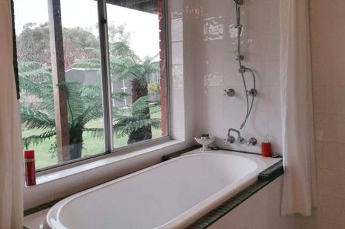 a white bath tub in a bathroom with a window at By The Bay in Kingston Beach