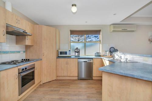 a large kitchen with wooden cabinets and a window at The Lighthouse - Port Willunga - C21 SouthCoast Holidays in Port Willunga