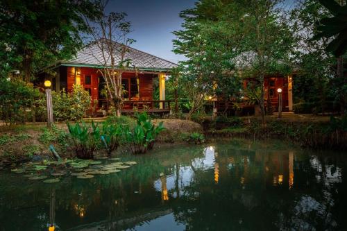 a house with a pond in front of it at Maikaew Damnoen Resort in Damnoen Saduak
