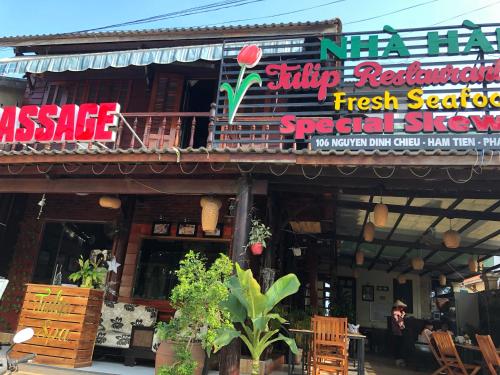 a restaurant with a sign on the side of a building at Tulip Mui Ne in Phan Thiet