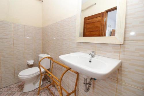 een badkamer met een wastafel, een toilet en een spiegel bij Dega Gardens in Canggu