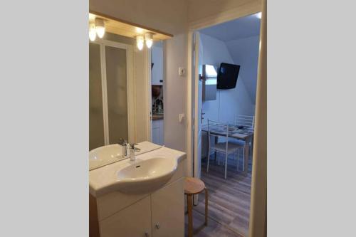 ein Bad mit einem Waschbecken und ein Zimmer mit einem Tisch in der Unterkunft Studio Cosy Douillet et Fonctionnel in Savigny-le-Temple