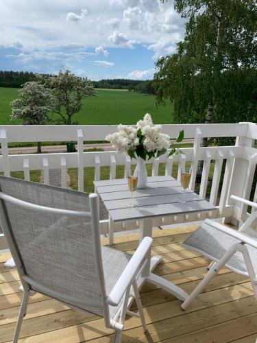 a white table with a vase of flowers on a deck at Rinkeby Gård in Jönåker