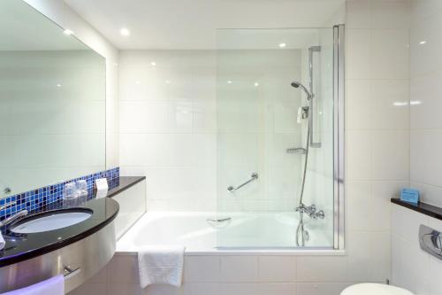 La salle de bains est pourvue d'une baignoire, d'un lavabo et d'une douche. dans l'établissement Holiday Inn Express Lisbon-Oeiras, an IHG Hotel, à Oeiras