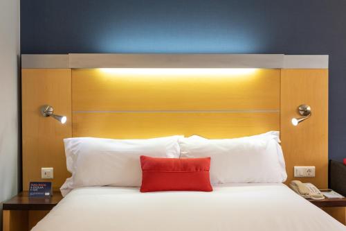 a bedroom with a large bed with a red pillow at Holiday Inn Express Lisbon-Oeiras by IHG in Oeiras