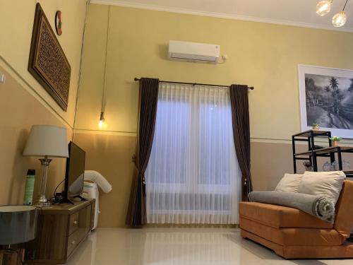 Una sala de estar con un sofá y una ventana. en Embay House & Private Pool, en Bogor