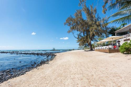 a sandy beach with umbrellas and the ocean at Voile Bleue Boutique Hotel in Trou aux Biches