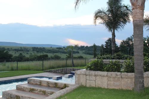 a swimming pool with stairs and a palm tree at Country Park Guest House - Muldersdrift in Muldersdrift